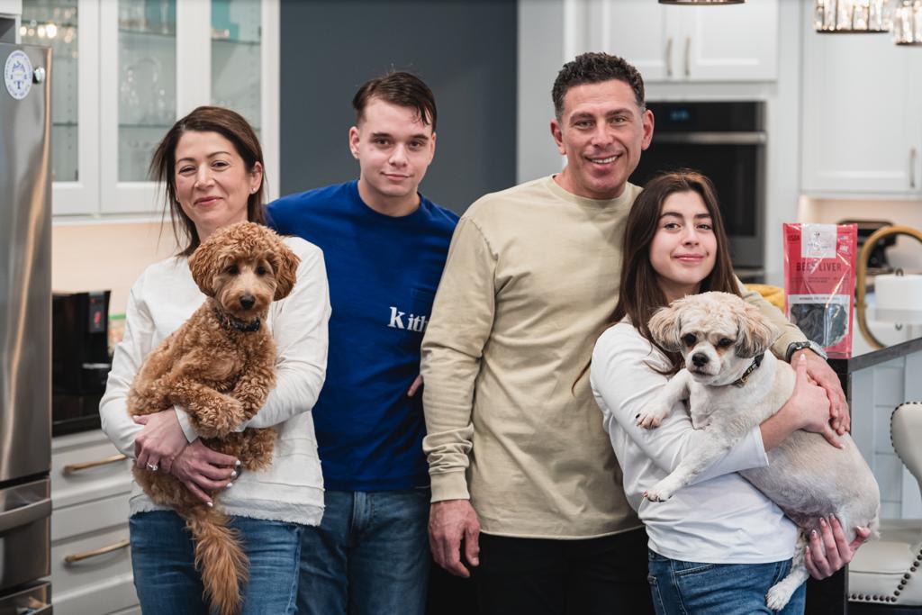 Family posing with two dogs in a home kitchen