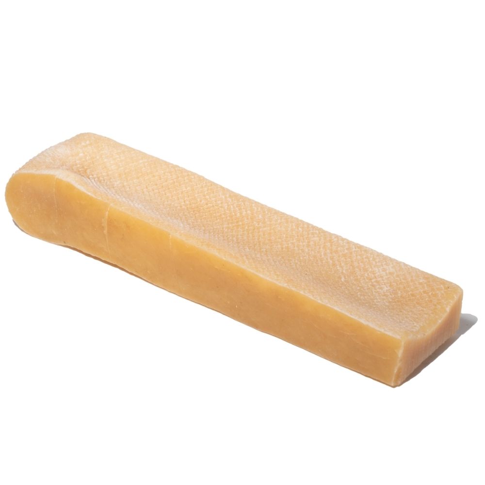 Angled top-down view of a small Himalayan yak cheese chew bar showing its firm rectangular shape and textured surface on a white background